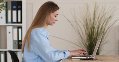 Dizüstü bilgisayarda yazı yazan genç bir kadın, yan görünüm