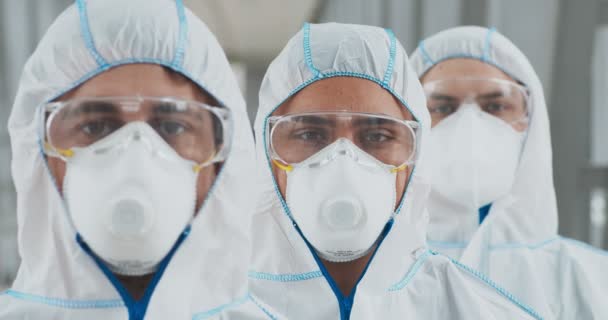 Tehlikeli madde giysisi giymiş bir grup adam halka açık yerleri dezenfekte etmeye hazır. — Stok video