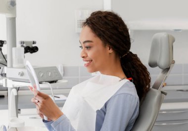 Güzel siyah bayan aynada beyaz gülüşünü kontrol ediyor.