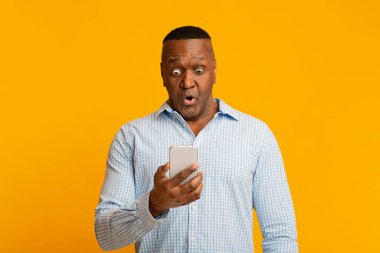 Olgun Afrikalı adam cep telefonundan mesaj okuyor.