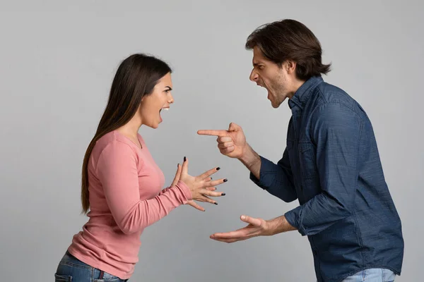 Millennial pareja peleando, gritando y culpándose unos a otros sobre fondo claro —  Fotos de Stock