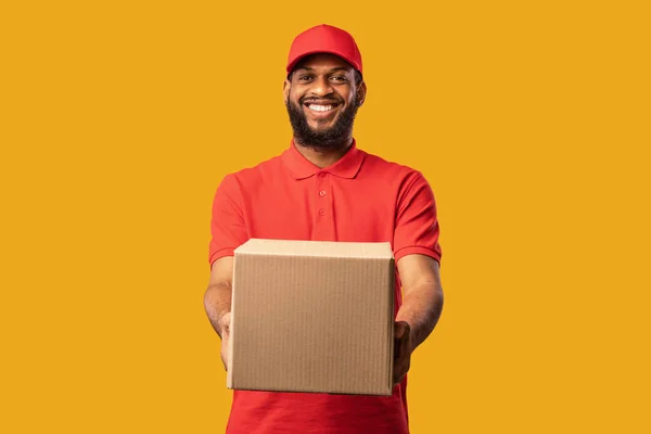 Mensajero africano que ofrece la caja de cartón a la cámara sobre fondo amarillo — Foto de Stock