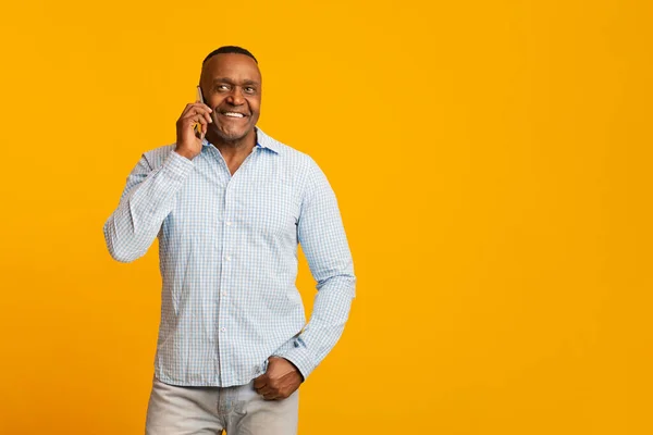 Vrolijke Afrikaanse man van middelbare leeftijd met praten op mobiele telefoon — Stockfoto