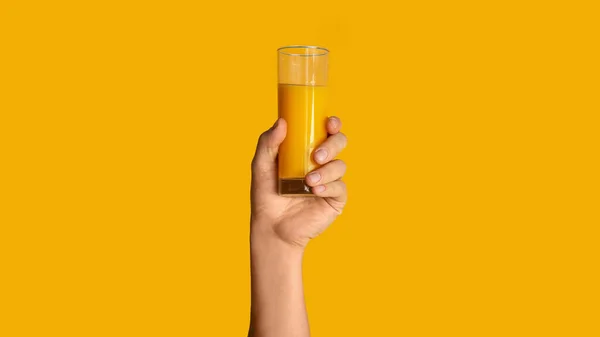 Close up of male hand showing glass with orange juice on color background, panorama — Stock Photo, Image