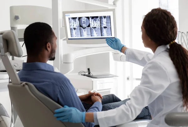 Γυναικείος οδοντίατρος δείχνει στην οθόνη με την εικόνα ακτίνων Χ — Φωτογραφία Αρχείου