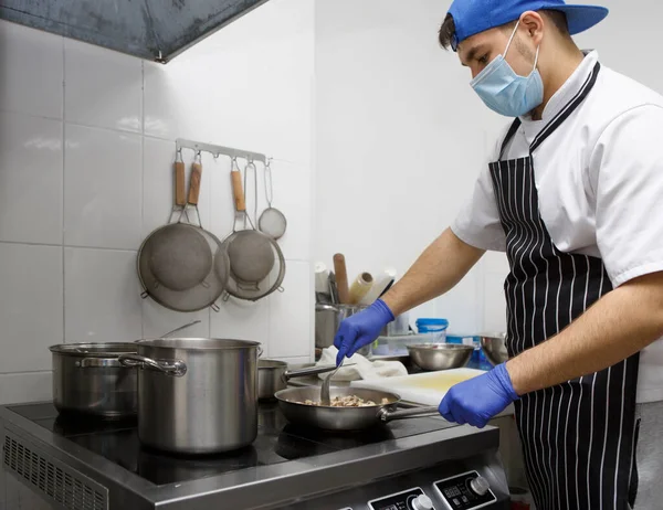 Man in protective mask and gloves cooking on kitchen — Stock Photo, Image