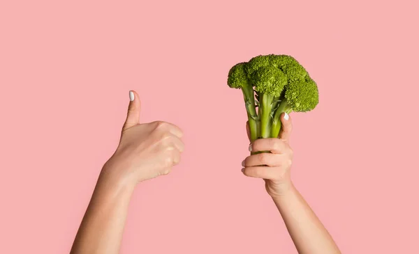 Zdrowe odżywianie i dieta. Młoda dziewczyna trzyma brokuły i pokazuje gest kciuka w górę na różowym tle, panorama — Zdjęcie stockowe
