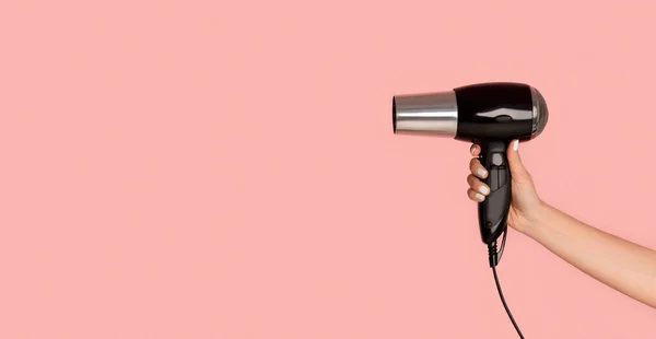 Unrecognizable girl showing hairdryer on pink background, empty space. Panorama — Stock Photo, Image