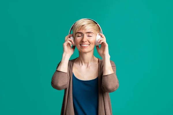 Mulher sorridente com fones de ouvido sem fio, espaço livre — Fotografia de Stock