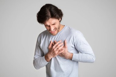 Acı dolu ifadesiyle göğüs ağrısı çeken bir adam.