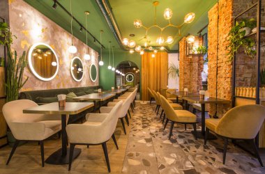 Masaları ve kanepeleri olan modern bir restoran, açık yeşil duvarlar.