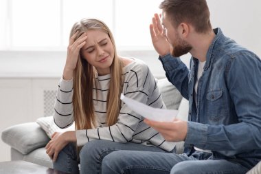 Kızgın koca banka hesap özetiyle suçlu karısına bağırıyor.