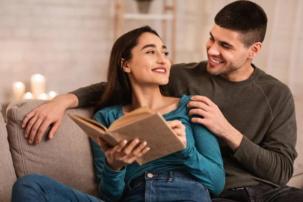 Adorável casal sentado no sofá leitura livro juntos — Fotografia de Stock