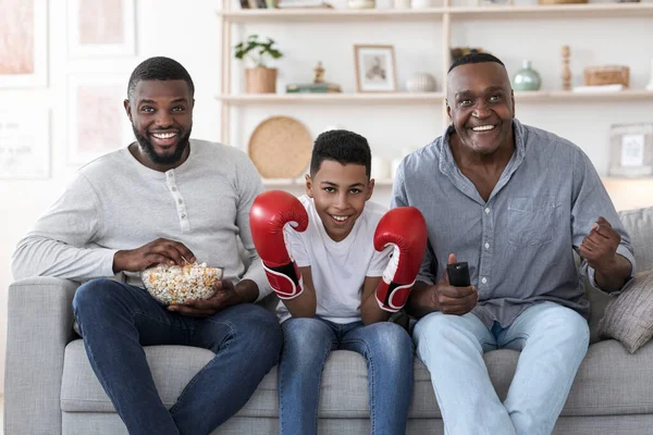 Excited Black Father, Son And Grandfather Watching Boxing Match On TV