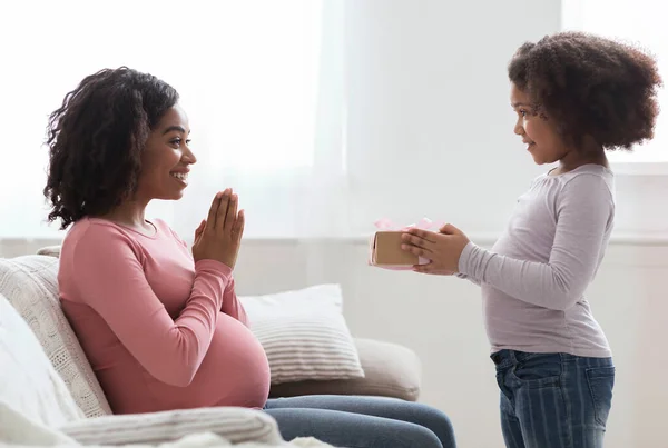 Pregnant Black Mom Receiving Gift From Her Little Daughter At Home