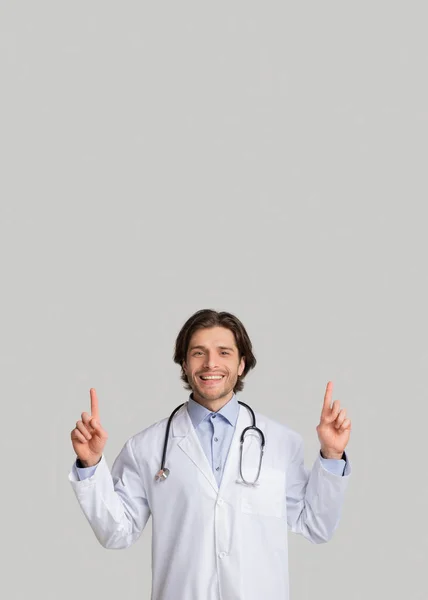 Όμορφος άνδρας γιατρός δείχνει με τα δάχτυλα το χώρο αντίγραφο πάνω από το κεφάλι του — Φωτογραφία Αρχείου