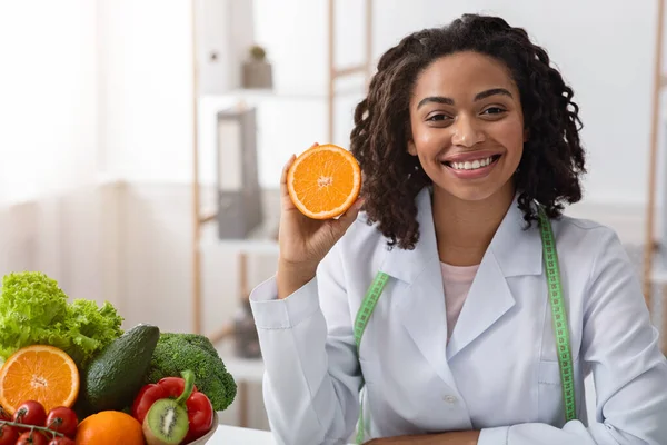 Веселая женщина-диетолог держит свежую оранжевую половину — стоковое фото