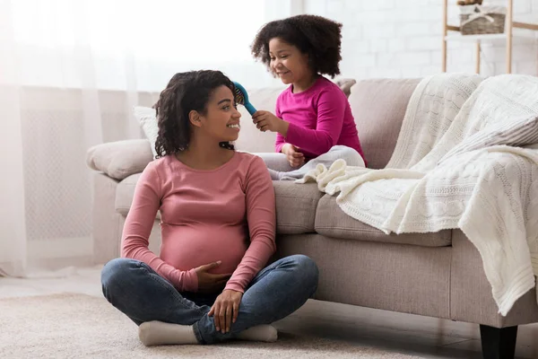 可爱的Toddler黑人女孩为她快乐的怀孕妈妈梳头 — 图库照片