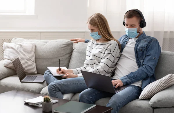 Couple of freelancers in protective masks working on laptops — Stock Photo, Image