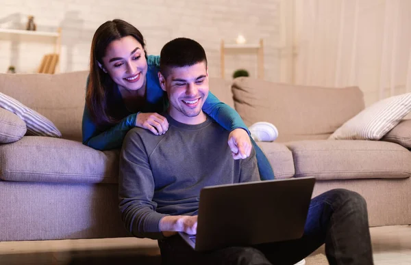 Šťastný pár pomocí PC sedí v útulném obývacím pokoji — Stock fotografie