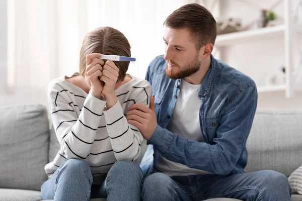 Upset couple sitting with negative pregnancy test result — Stock Photo, Image