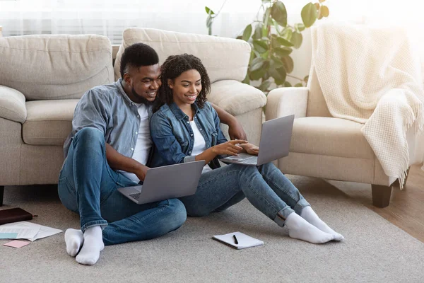 Trabalho remoto. Casal preto usando laptops em casa, trabalhando juntos online — Fotografia de Stock