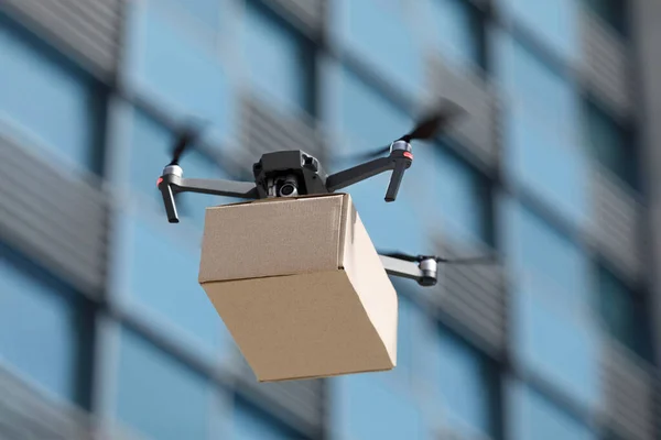 Drone moderno inteligente transportando parcela na cidade — Fotografia de Stock