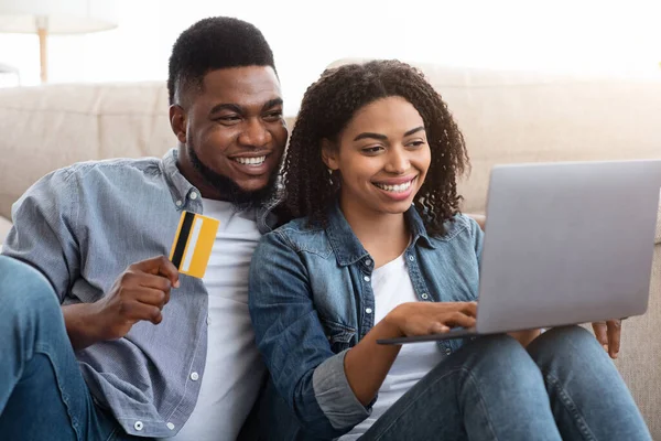 Μαύρο ζευγάρι που χρησιμοποιεί φορητό υπολογιστή και πιστωτική κάρτα για online αγορές στο σπίτι — Φωτογραφία Αρχείου
