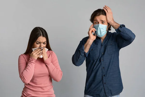 Bezorgde man in beschermende masker praten op mobiele telefoon naast zieke vriendin — Stockfoto