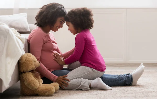 Glücklich schwanger schwarz frau und sie süß tochter bonding bei zuhause — Stockfoto