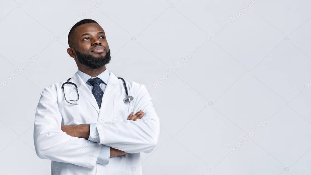 Happy medical doctor in white robe looking at copy space