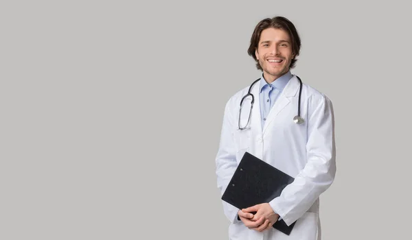 Retrato de médico interno feliz em uniforme com prancheta nas mãos — Fotografia de Stock