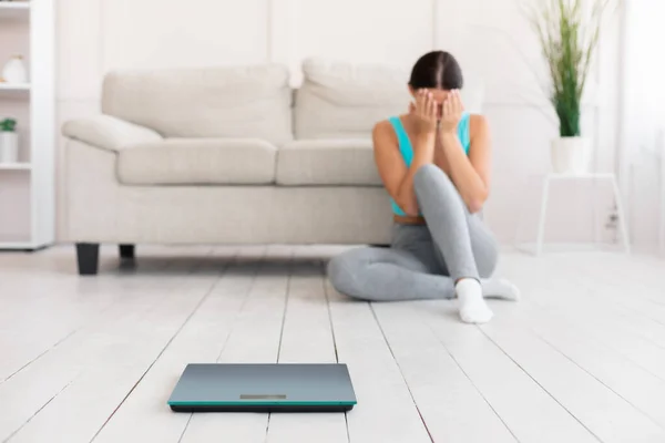 Kvinnan gråter sitter nära vikt skalor få kilogram hemma — Stockfoto