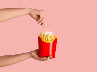 KHARKIV, UKRAINE - 4 Nisan 2020: Pembe arka planda McDonalds 'dan bir paket patates kızartması taşıyan genç kız