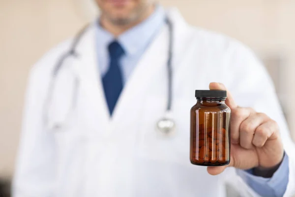 Mature experienced doctor holding jar for pills — Stock Photo, Image