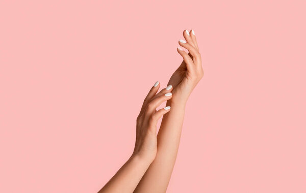 Female hands with perfect silky skin and natural manicure on pink background, close up