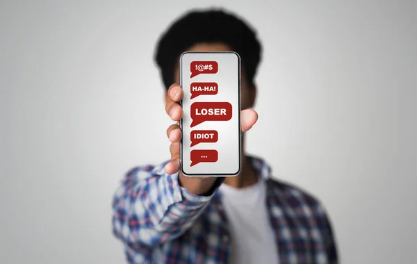 Siber zorbalık konsepti. Ekranda küfürlü mesajlar içeren akıllı telefon gösteren Afro-Amerikalı bir adam. Kolaj — Stok fotoğraf