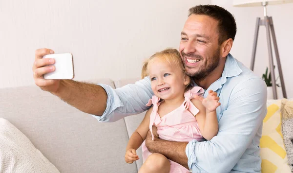 Sorrindo pai e menina tomando selfie em casa — Fotografia de Stock