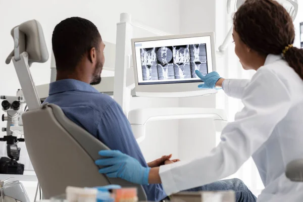 Kadın dişçi ve erkek hasta dijital ekranda röntgen izliyor. — Stok fotoğraf