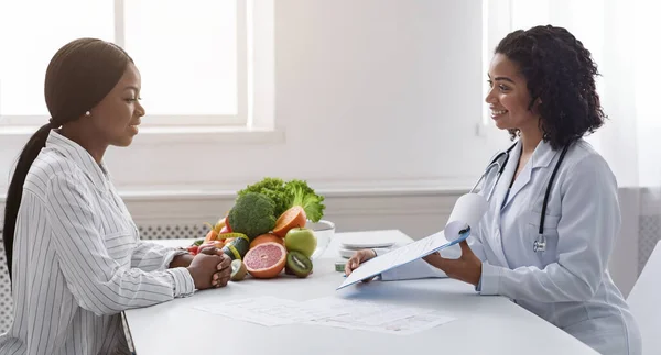 Duas senhoras negras paciente e médico conversando na clínica — Fotografia de Stock