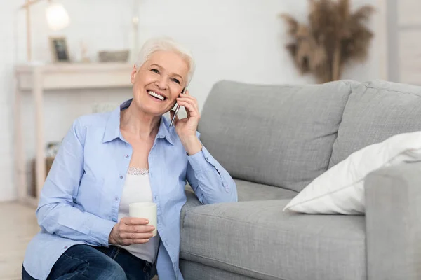 Улыбающаяся пожилая женщина с приятным телефонным звонком дома — стоковое фото