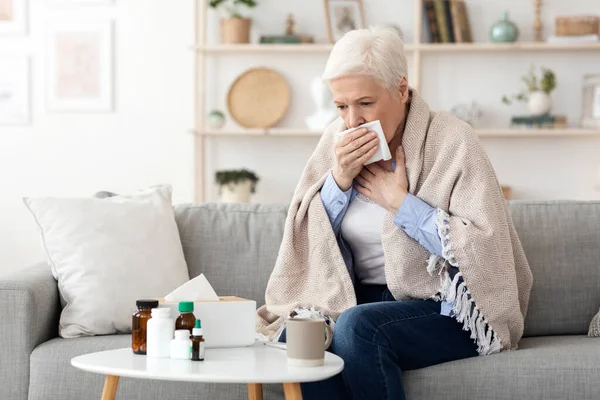 Συμπτώματα από τον ιό του κερατοειδούς. Άρρωστη ηλικιωμένη γυναίκα που βήχει δυνατά στο σπίτι — Φωτογραφία Αρχείου