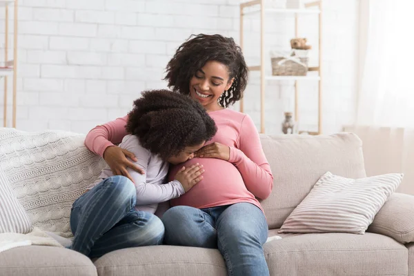 可爱的小非洲女孩亲吻和拥抱她怀孕的妈妈肚子 — 图库照片