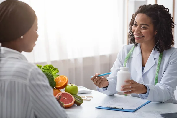 Mujer negra dietóloga recomendando tabletas a paciente femenina —  Fotos de Stock