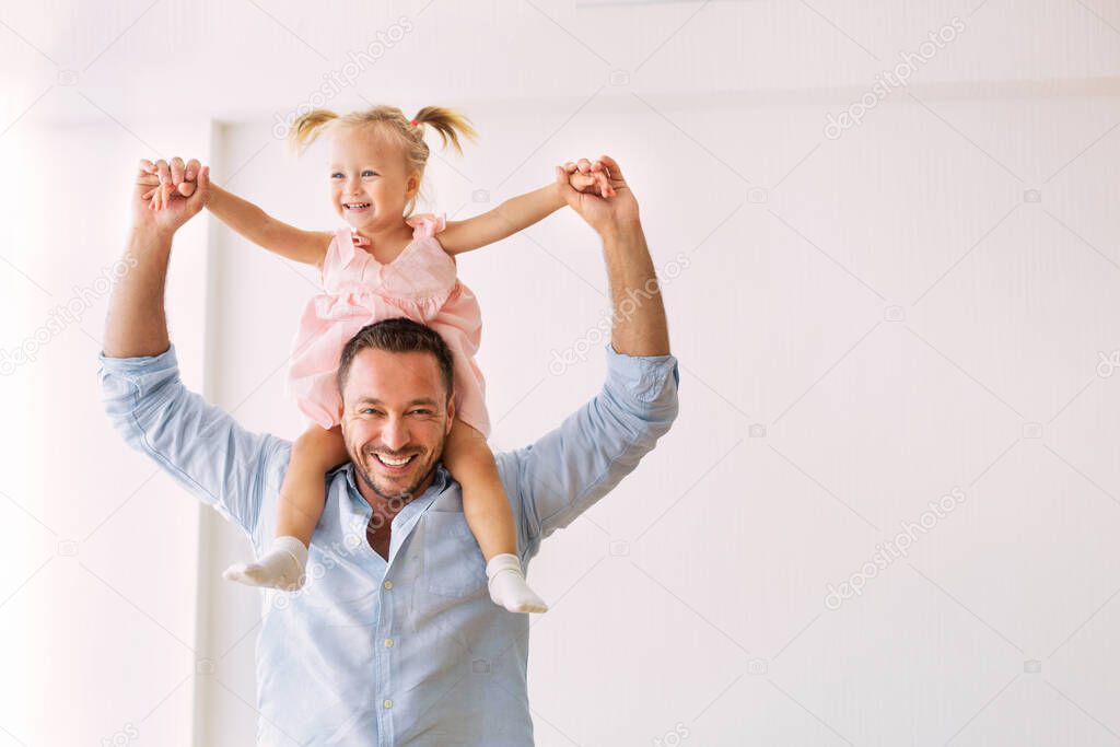 Millennial father riding his cute daughter on shoulders