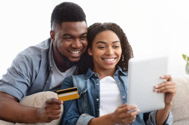 İnternetten alışveriş. Evli Afrikalı çift internetten dijital tabletle mal alıyor.