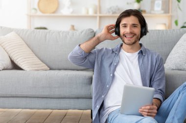 Duygusal adam dijital tablet kullanıyor, müzik dinliyor.