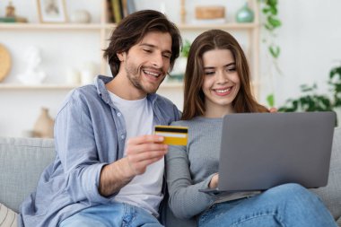 Çevrimiçi alışveriş için kredi kartı kullanan pozitif bir çift.