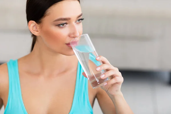Sportif kız evde oturmuş bir bardak su içiyor. — Stok fotoğraf