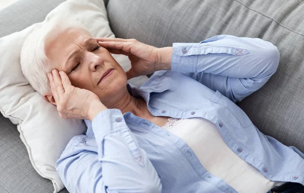 Migrena la vârsta înaintată. O femeie în vârstă care are dureri de cap puternice acasă — Fotografie, imagine de stoc